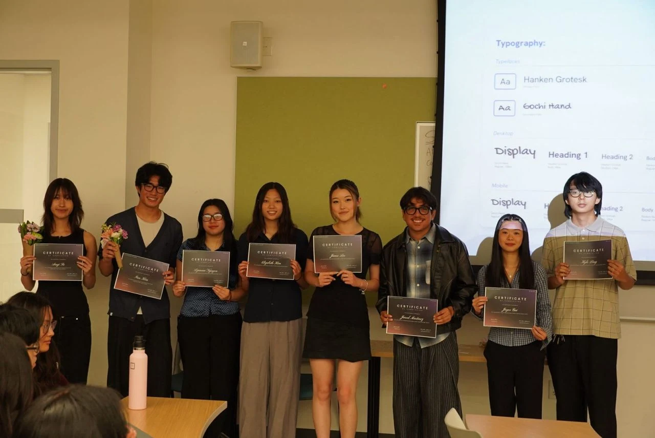 The #Include design team holding certificates of completion at Demo Day, in front of a slide showing the Linguistics Club typography